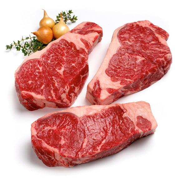 Three raw steak pieces on a white background with onions and herbs.