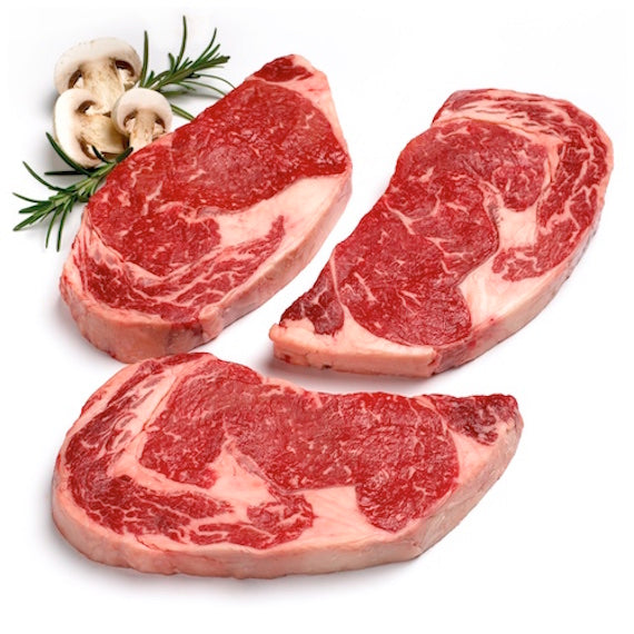 Three raw steak portions with mushrooms and rosemary on a white background