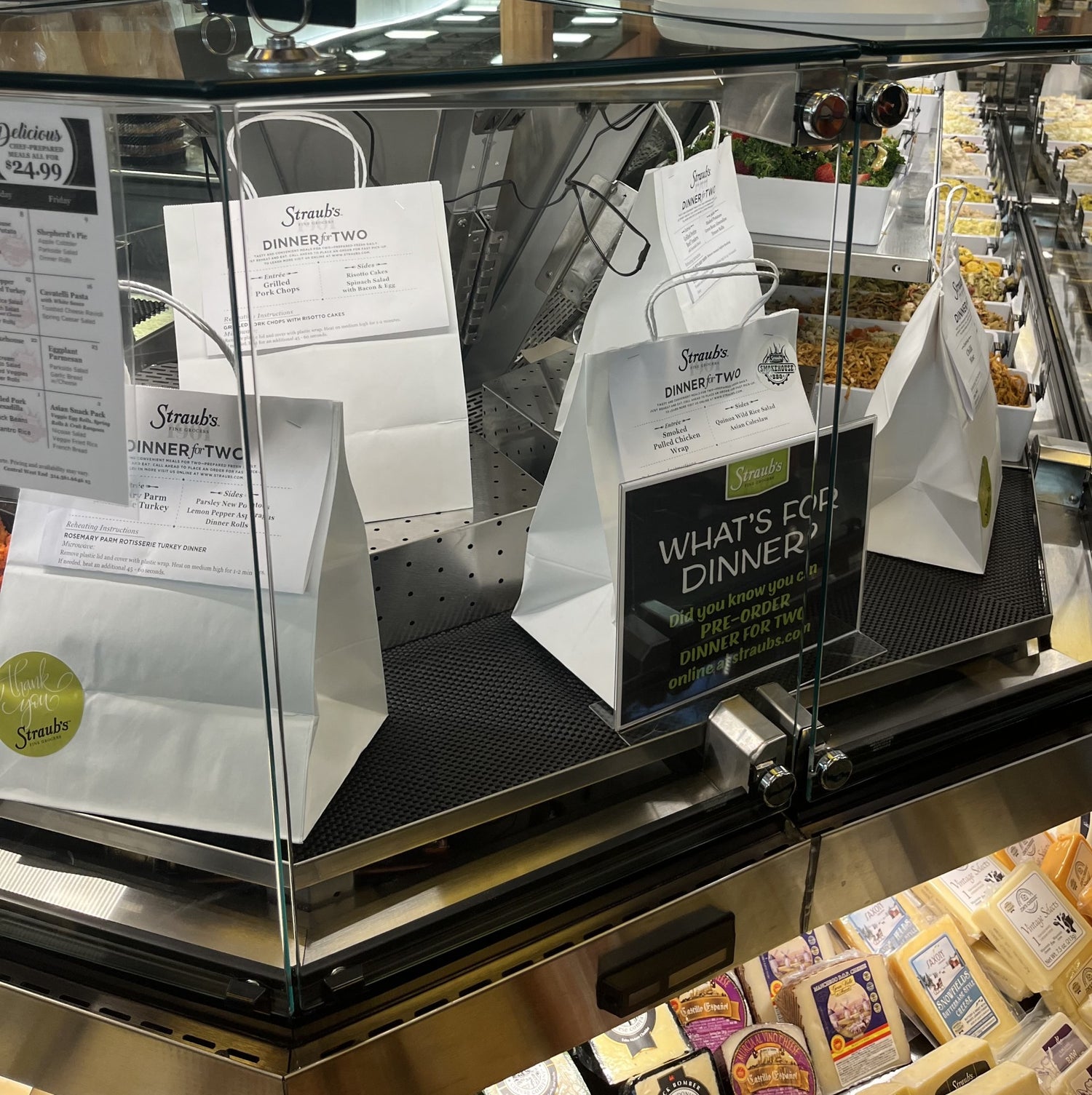 Bags of prepared dinners behind a deli case.